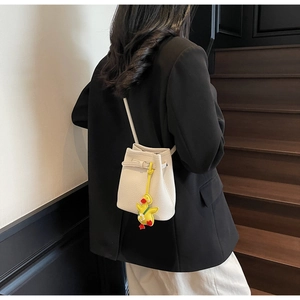 Detailed view of white lychee leather bucket bag with a cute yellow duck pendant charm