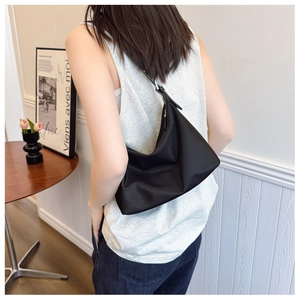Detail view of the black minimalist nylon shoulder bag with silver metal buckle on strap
