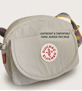 Detail of grey nylon crossbody bag featuring colorful striped strap and brand badge