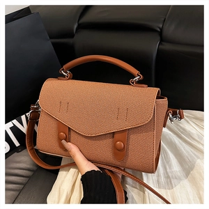 Detailed view of brown woven texture handbag with silver metal buckles and adjustable strap