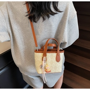 Dettaglio di una mini borsa a secchiello con trama a cuore e ciondolo a coniglio