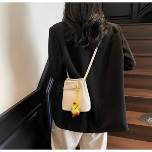 Detail of cream bucket bag featuring lychee texture leather and yellow duck charm detail