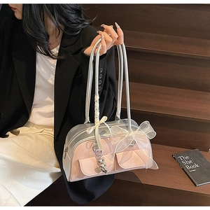 Detail of silver and pink saddle bag featuring white mesh bow and heart pendant charm