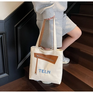 Détail du sac cabas en toile blanc cassé avec garniture en cuir brun et broderie TELN