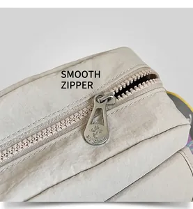 Detail of smooth silver flower zipper head on a cream fabric shoulder bag with laptop