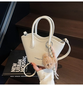 Détail du sac seau en cuir grainé blanc avec breloque ours et bandoulière