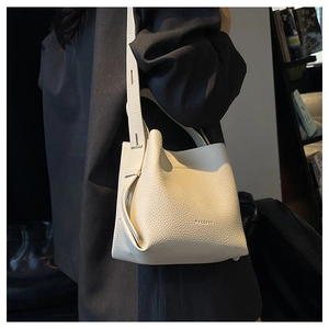 Close-up of cream lychee texture bucket bag with adjustable strap and brand logo