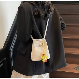 Detail of off-white lychee pattern bucket bag with a yellow cartoon duck pendant detail