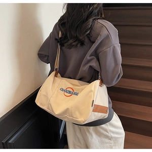 Détail d'un sac cabas en toile beige avec broderie et garniture en cuir brun
