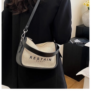 Detail of canvas crossbody bag with letter print shown on model in modern setting