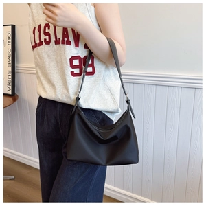 Side view of a minimalist black hobo bag with adjustable strap worn by a model