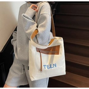 Gros plan d'un sac cabas en toile blanche avec poche en cuir et sangle tissée