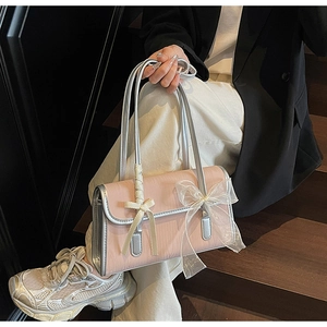Detail of pink shoulder bag with bow accents and silver trim in a lifestyle setting