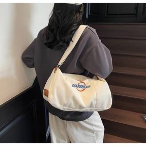 Gros plan sur le sac bandoulière en toile blanche avec détail cercle orange et sangle