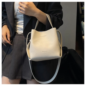 Detail of lychee pattern leather and embossed logo on the beige bucket bag