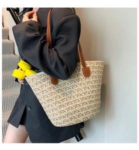 Dettaglio della borsa tote in paglia intrecciata con manici in pelle marrone e righe