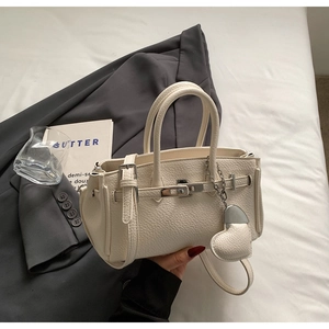 Dettaglio della borsa in ecopelle crema con chiusura in metallo e ciondolo a cuore