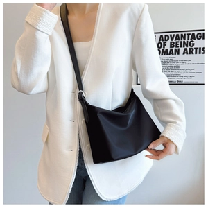 Close-up of minimalist black nylon tote bag featuring an adjustable leather strap and smooth finish