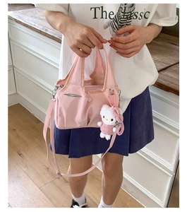 Detail of pink shoulder bag with metal trim, pleats, and white kitty plush charm