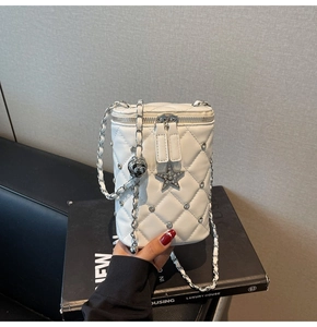 Détail du sac seau blanc matelassé avec breloque étoile en strass et chaîne en cuir
