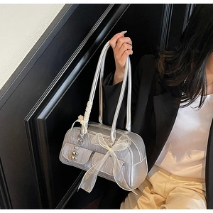 Detail of silver metallic saddle bag with organza bow and heart charm in Y2K style