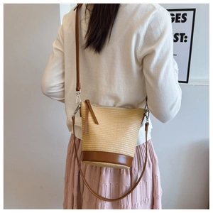 Model back view wearing straw bucket bag with brown leather strap and pink dress