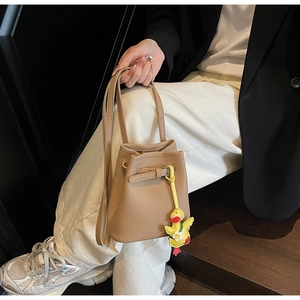 Brown lychee leather bucket bag with drawstring closure and yellow duck pendant charm