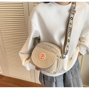Close-up of beige nylon crossbody bag featuring jacquard wide strap on a model