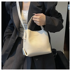 Close-up of beige lychee grain leather handbag featuring embossed brand text detail