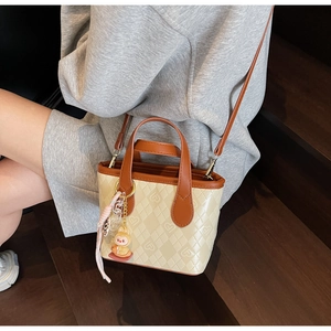 Dettaglio della borsa a secchiello beige trapuntata con lettere e charm a coniglio