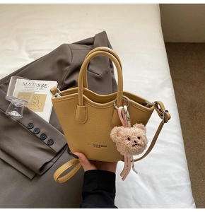 Détail du sac cabas jaune moutarde avec cuir texturé, ours en peluche et bandoulière tissée