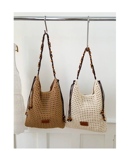 Detailed view of woven shoulder bag with beaded straps and faux leather logo patch