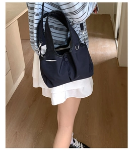 Detail of navy blue nylon pleated shoulder bag with adjustable strap and silver metal hardware
