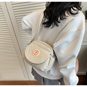 Detail view of off-white crossbody bag with brand logo and patterned shoulder strap