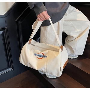 Détail du sac de voyage en toile avec broderie bleue et accents en cuir sur l'escalier