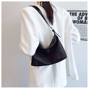 Detail of adjustable leather strap and silver metal buckle on black nylon tote bag