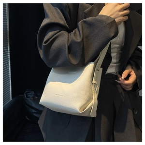 Detailed close-up of white lychee pattern leather shoulder bag with embossed logo