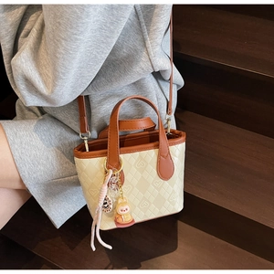 Dettaglio della borsa a secchiello in pelle PU crema con cuori a rilievo e ciondolo a coniglio