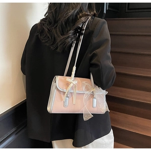 Detail of light pink shoulder bag with tulle bow and ribbon handle on a black blazer