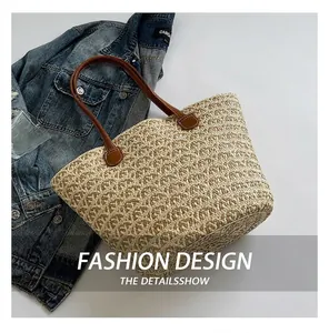 Dettaglio della borsa tote in paglia intrecciata con manici in pelle marrone su lenzuola