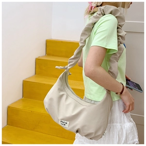 Modell mit cremefarbener geraffter Tasche auf einer leuchtend gelben Holztreppe