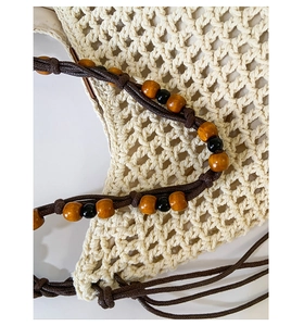 Detail of hollow woven beach bag with wooden bead accents and cotton texture