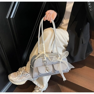 Silver underarm bag featuring decorative white lace bows and heart charms on front pockets