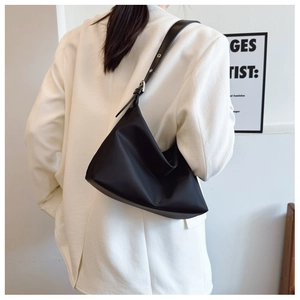 Detail of minimalist black hobo shoulder bag featuring adjustable strap and silver buckle