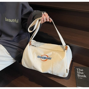 Détail du sac baril en toile blanche avec broderie et bordures en cuir marron