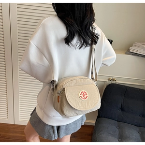 Detailed view of the beige nylon crossbody bag with adjustable printed wide shoulder strap