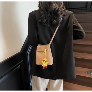 Detail of tan bucket bag with lychee texture and cute yellow duck charm on a model