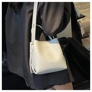 Detailed view of white lychee-patterned leather bucket bag with shoulder strap and logo