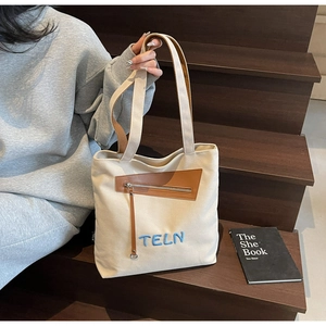 Détail du sac en toile avec broderie TELN et poche zippée diagonale avec tirette en cuir