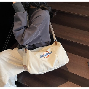 Détail du sac cabas en toile avec imprimé lettres et accents de bandoulière en cuir brun